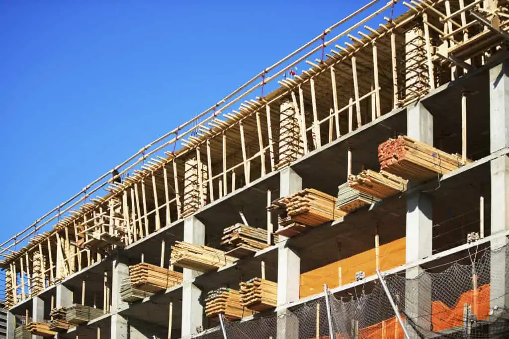 Construction site showing building framework with scaffolding and safety barriers.